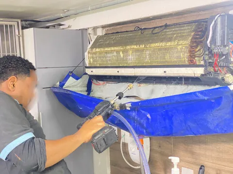 Técnico da Ice Mais fazendo a higienização de um split, com a capa de proteção azul